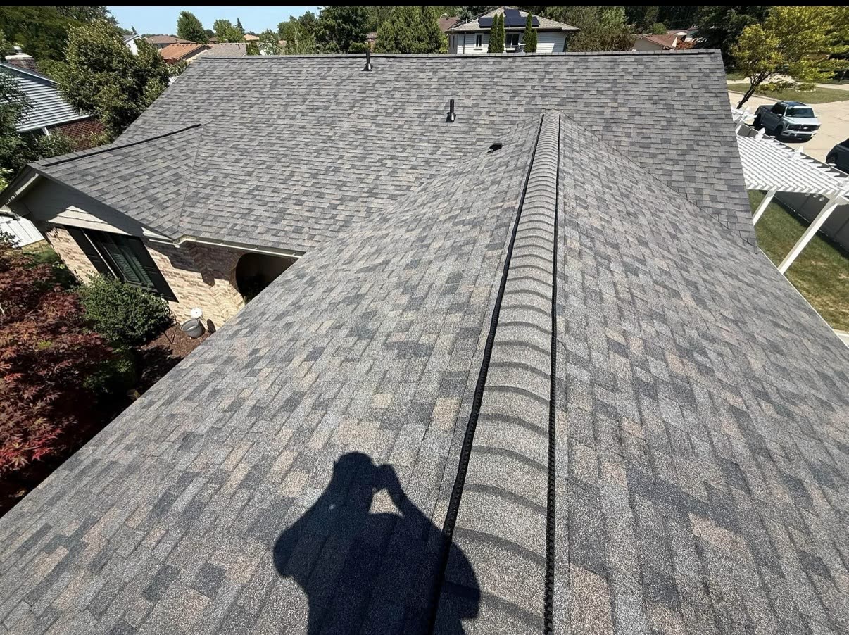 Close view of charcoal architectural asphalt shingles with a ridge vent running down the center of the roof