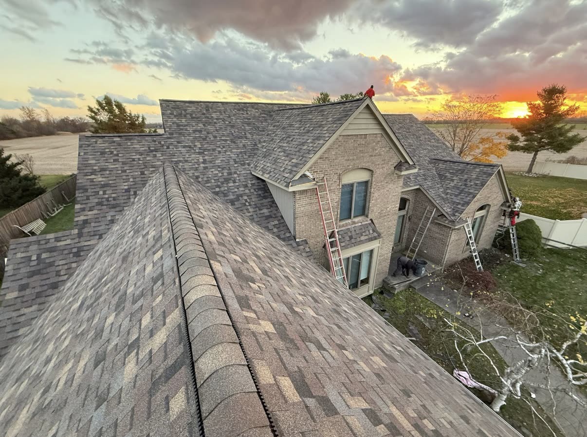 Completed dark asphalt shingle roof on a two story brick home with an arched front entry and bay window