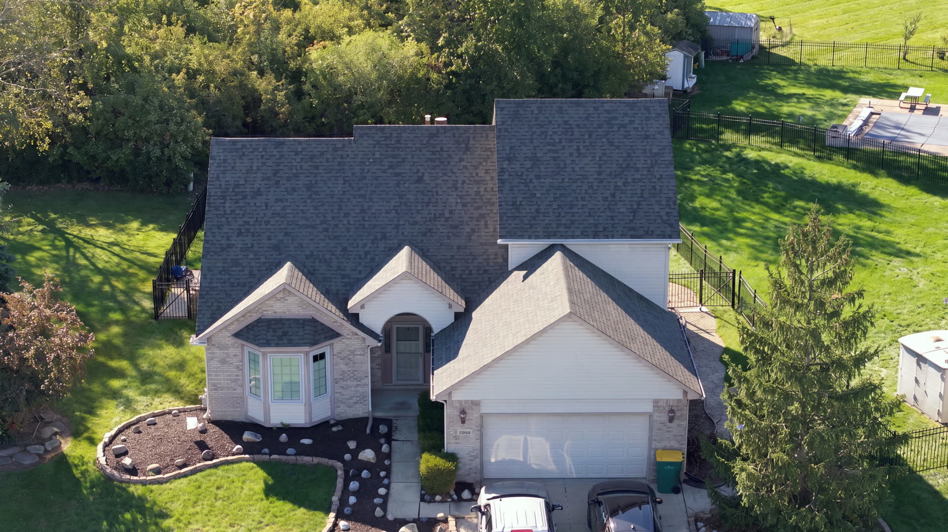 Aerial drone view of a completed grey architectural shingle roof on a brick ranch home