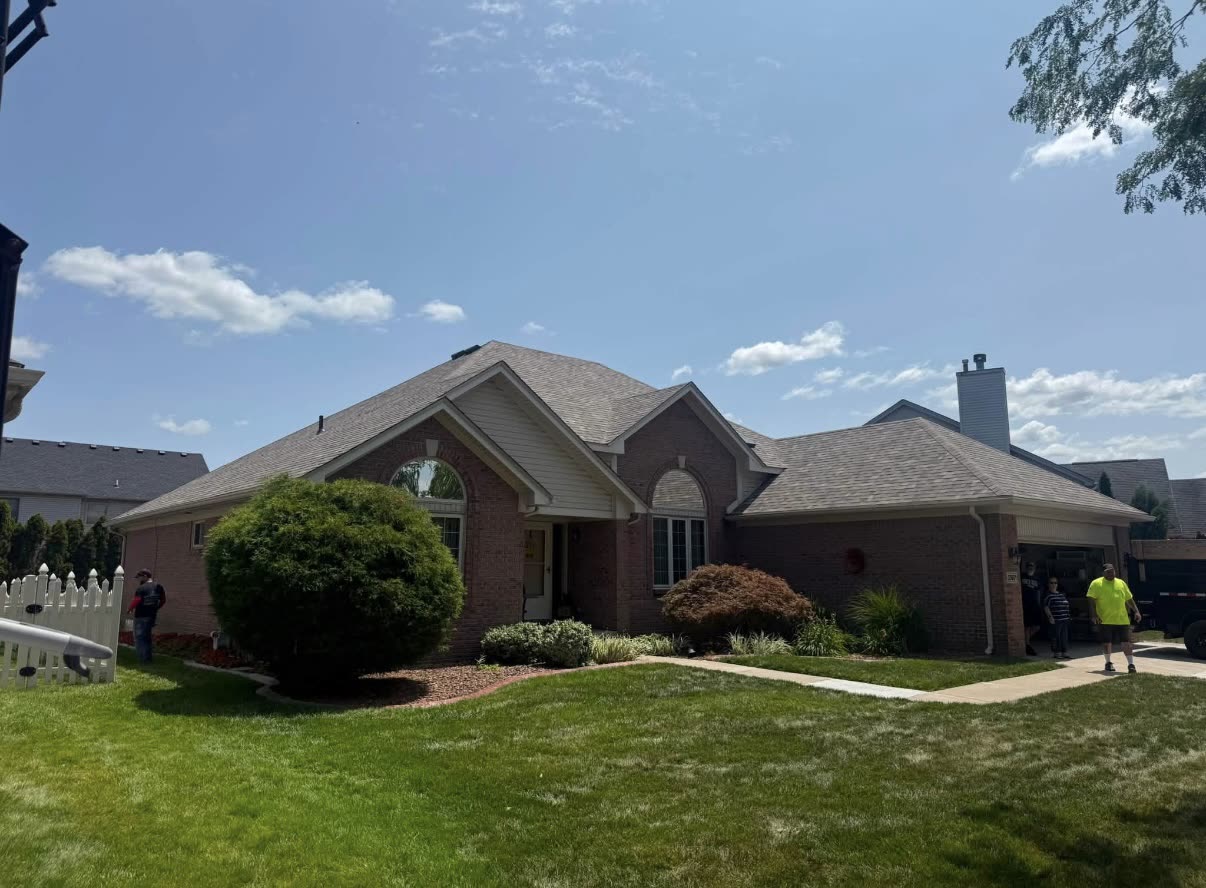 Completed grey and brown asphalt shingle roof on a single story brick ranch home with a brick chimney