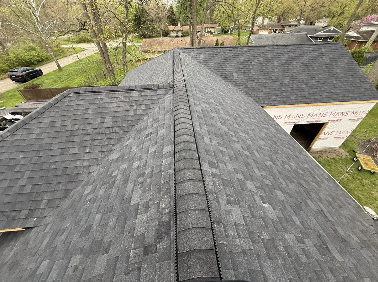 Completed multicolor architectural shingle roof on a home with a cross gable and a side dormer