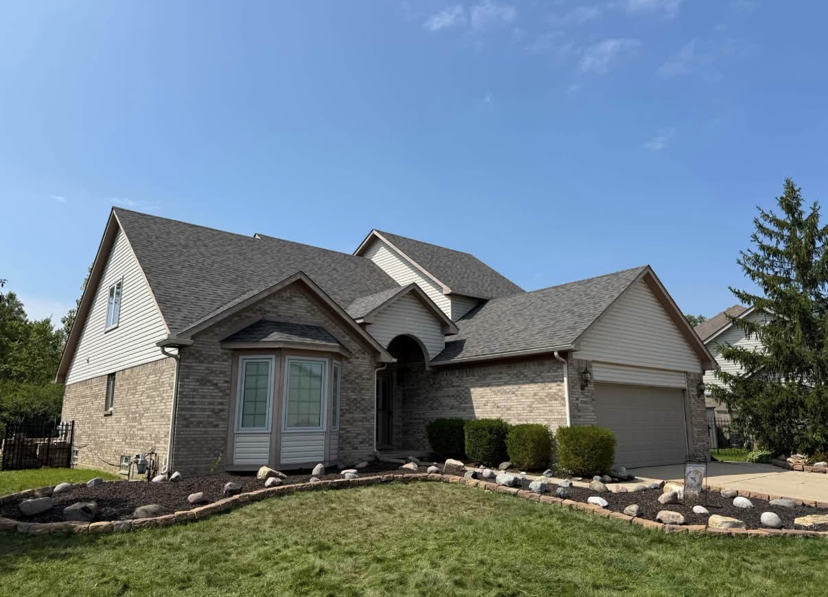 Completed grey asphalt shingle roof on a two story home with a two car garage, bay window, and arched entry