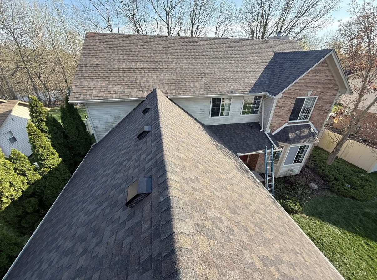 Aerial twilight view of a completed architectural asphalt shingle roof on a single story suburban home