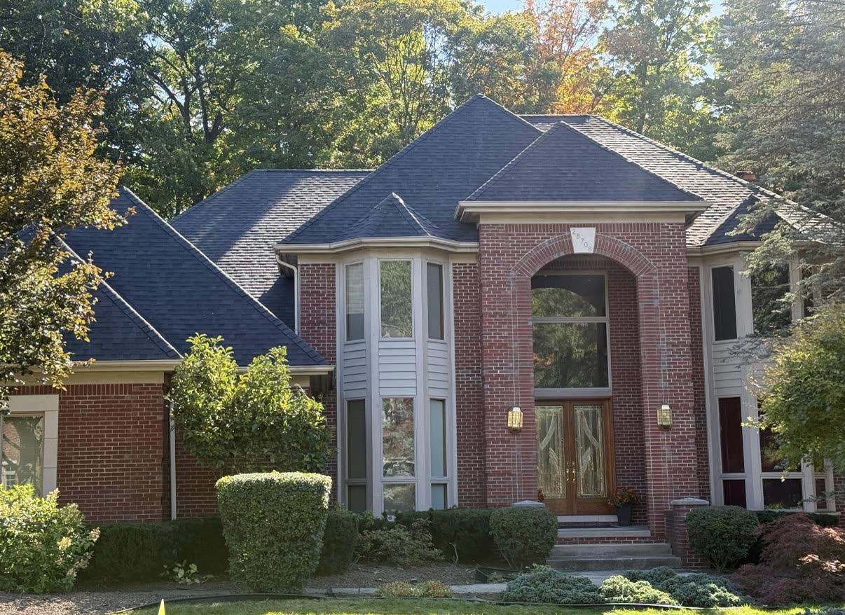 Aerial view of synthetic underlayment installed across a roof deck with bundles of new architectural shingles staged on top