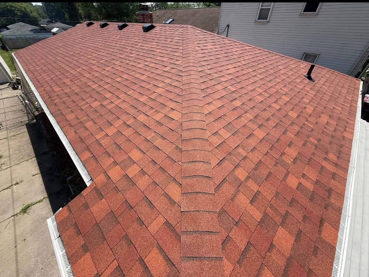 Close view of warm brown and red toned architectural asphalt shingles on a completed residential roof